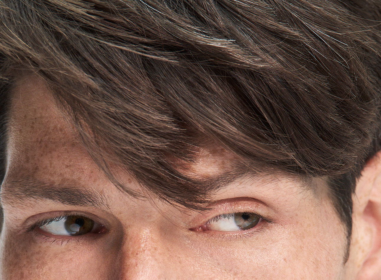 Close-up of a young man's face with styled hair and expressive eyes.