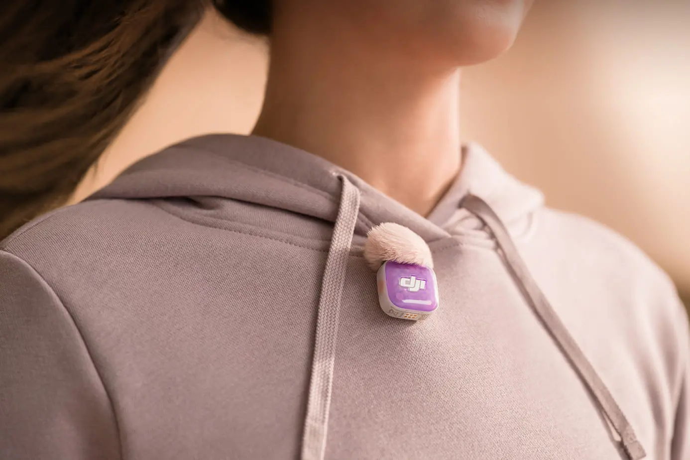 A close-up of a person wearing a hoodie with a DJI Mic Mini 2S attached.