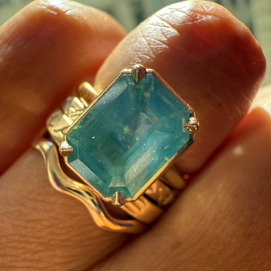 Emerald cut teal opalescent sapphire ring stacked with wedding bands