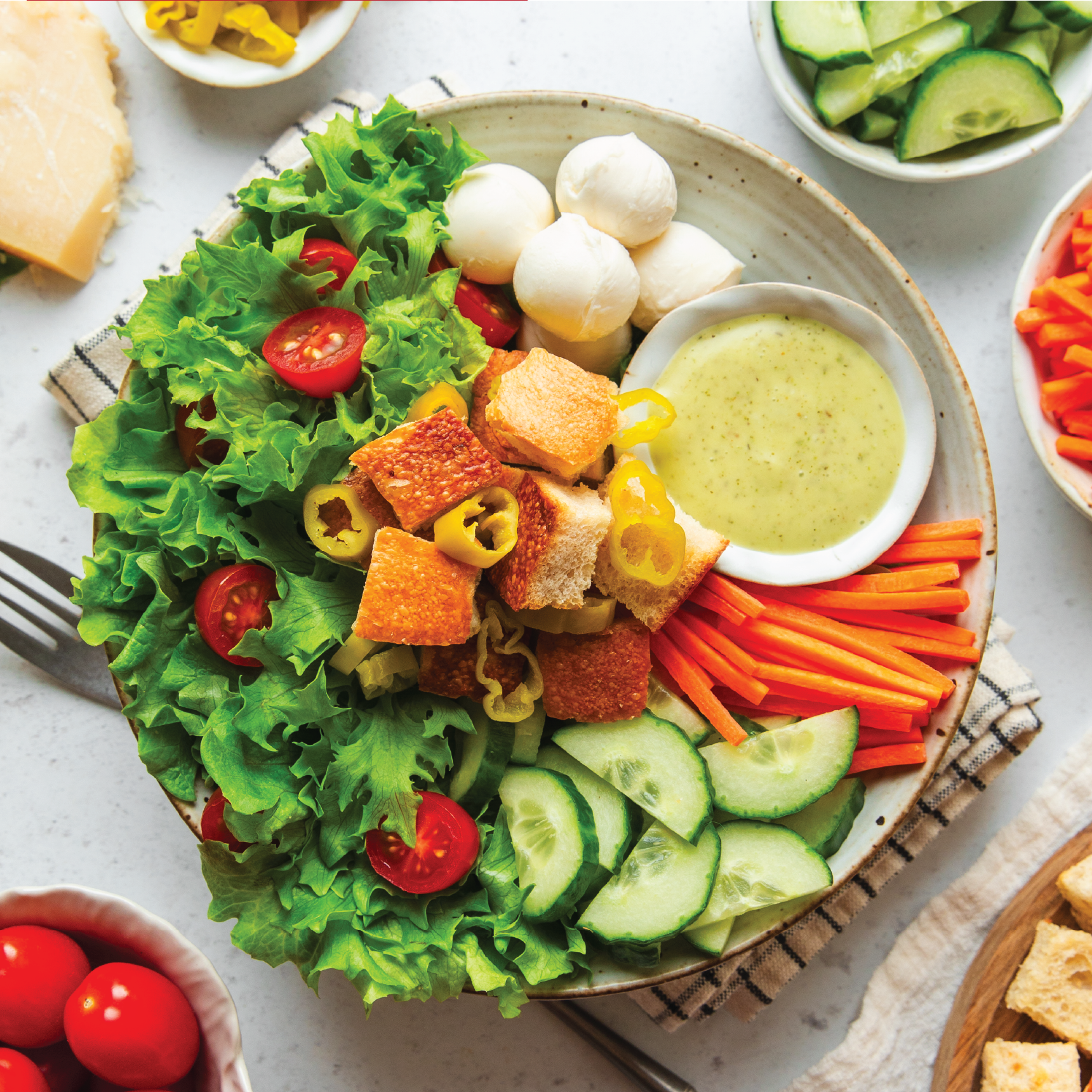 A colorful salad with greens, cherry tomatoes, cucumbers, and dressing.