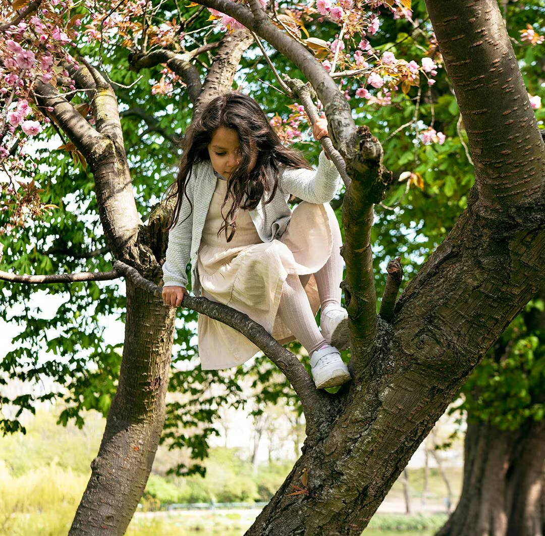 Girl clambering down from a tree – it’s in flower and has just the right sort of branches to be lots of fun to climb 