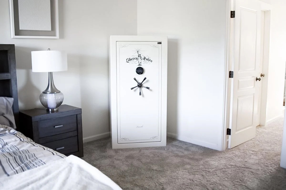 A bedroom with a white safe, lamp, and closed door.