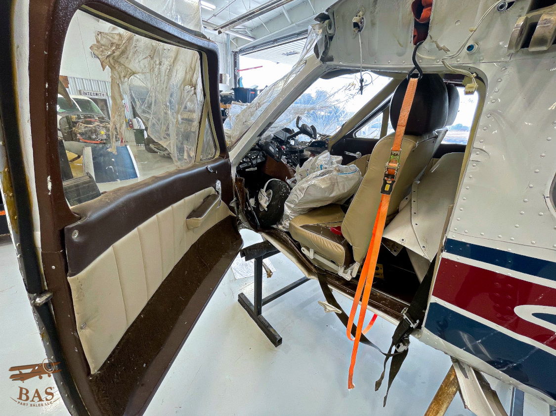 Interior view of a helicopter with an open door and pilot seat.