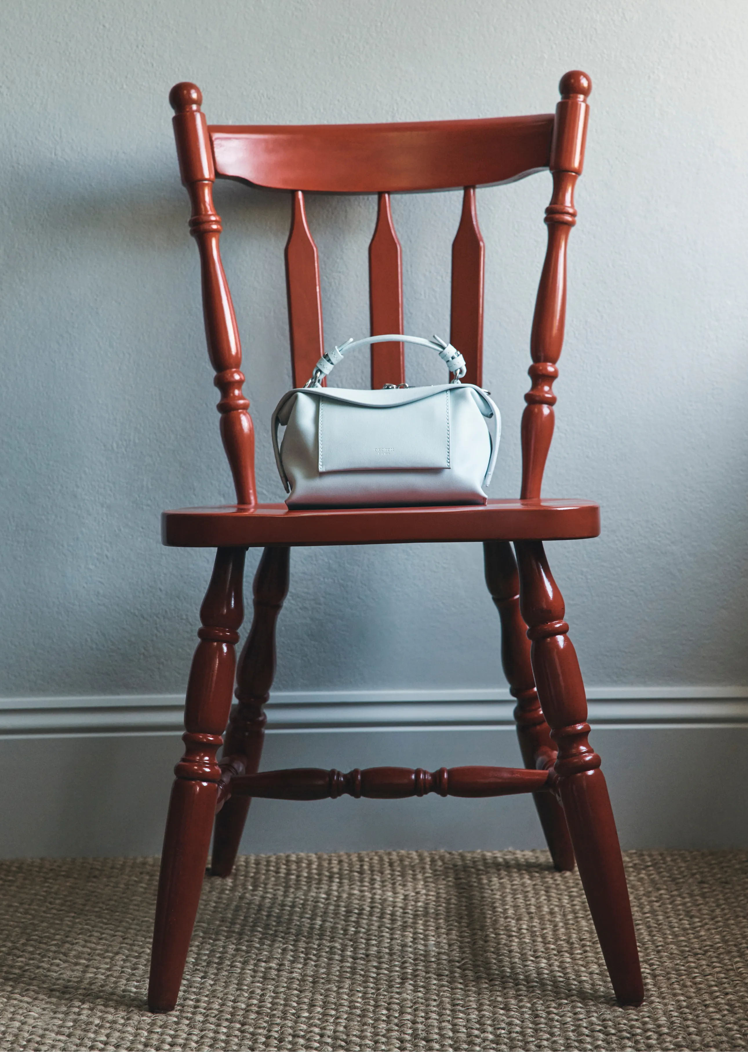 A red wooden chair with a small white handbag on it.