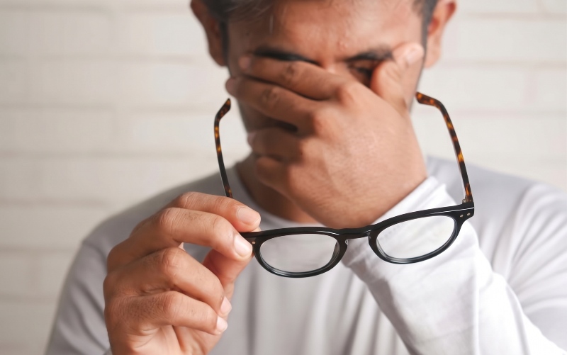 man with eye fatigue holding Dash Black eyeglasses