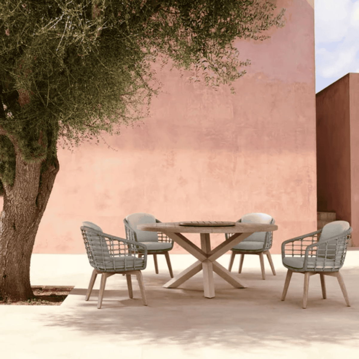 Outdoor dining table and chairs placed beneath a shade tree for a comfortable desert patio dining design.