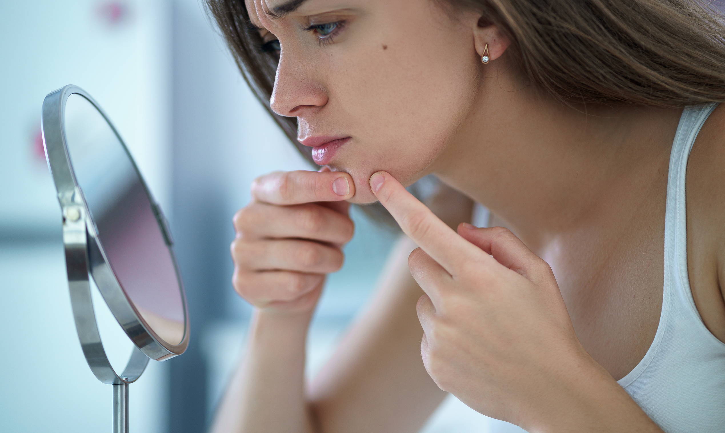 Girl checking acne in mirror