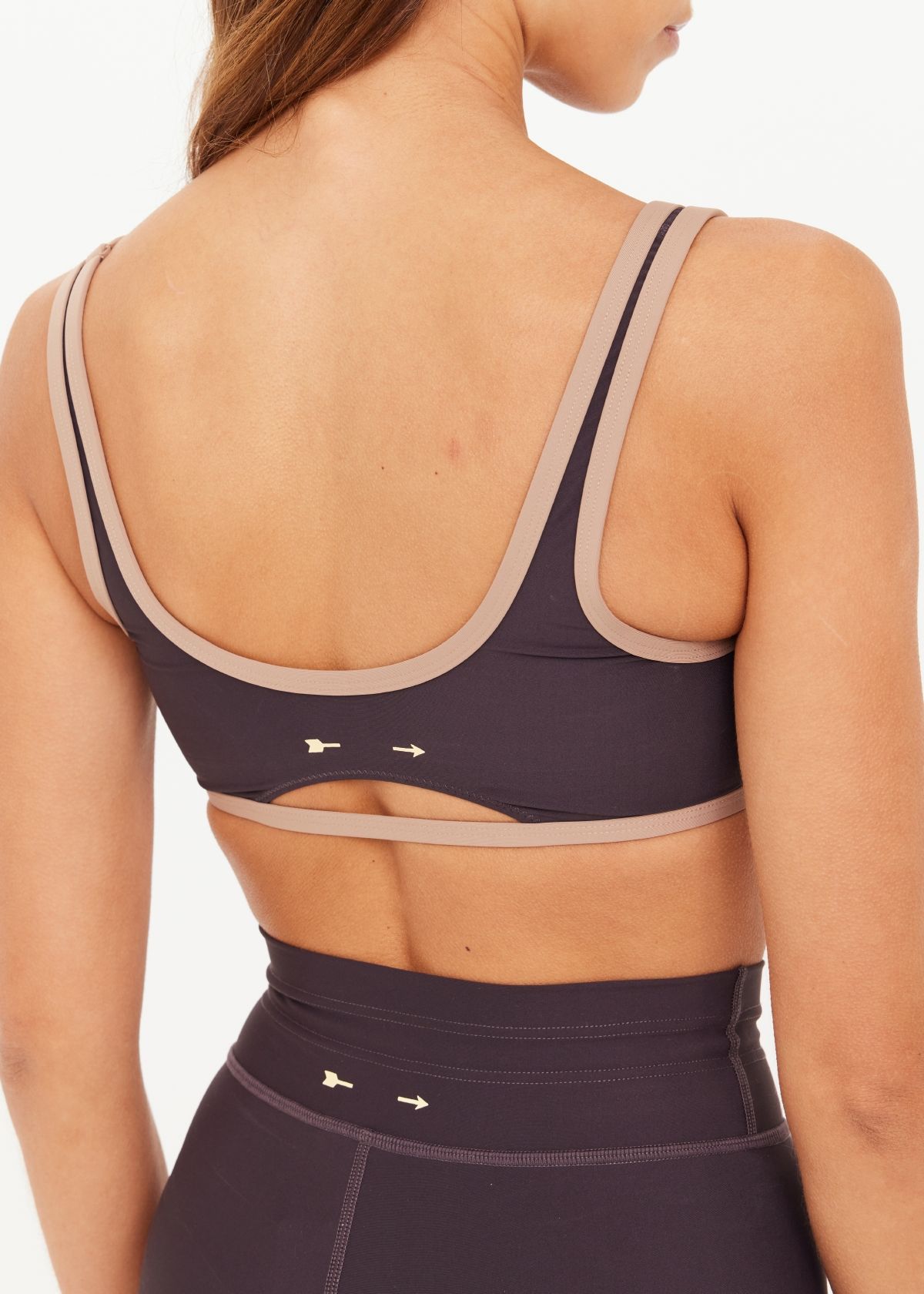 Woman wearing a dark sports bra and matching pants, posing confidently.