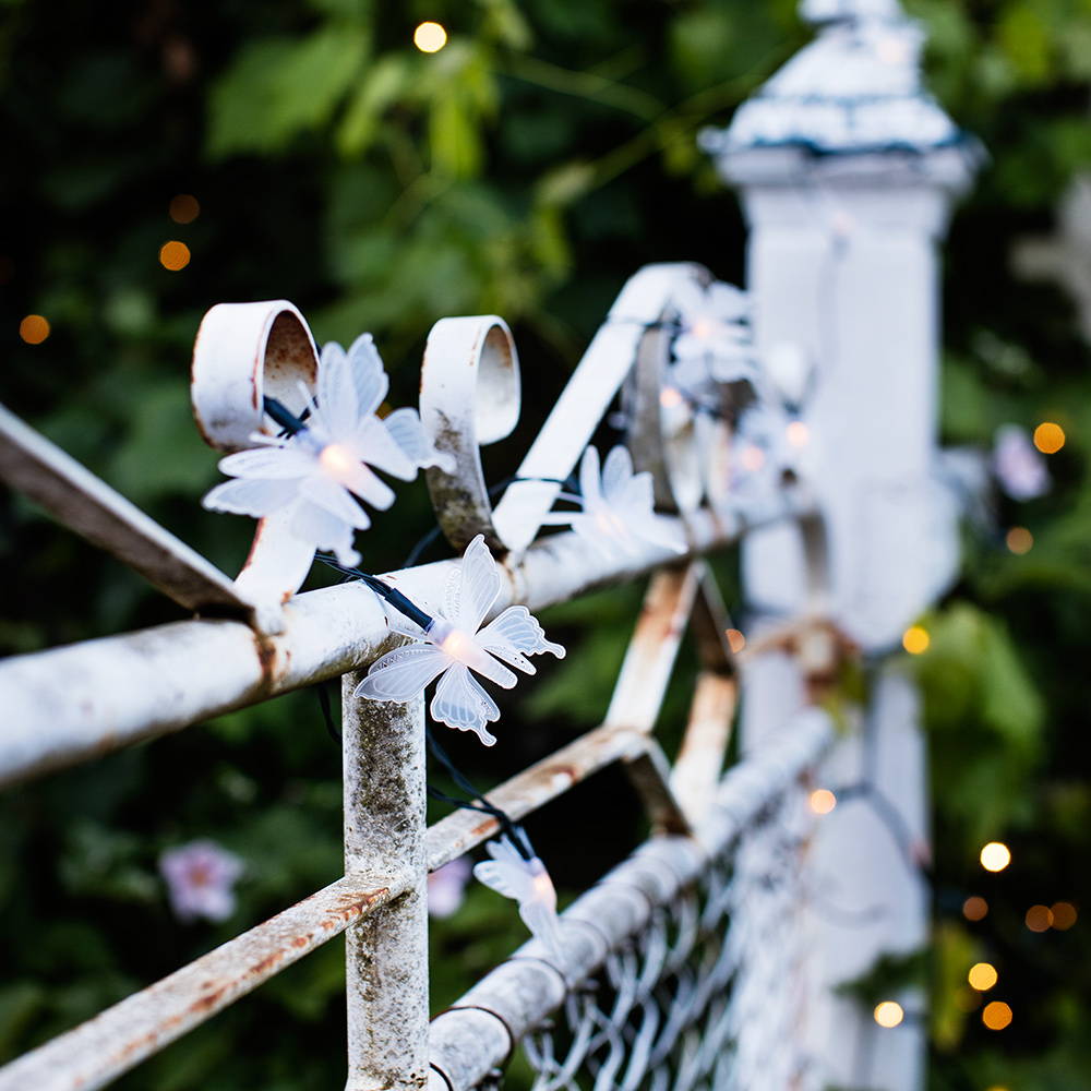 Solar butterfly LEDs entwined around a rustic white gate