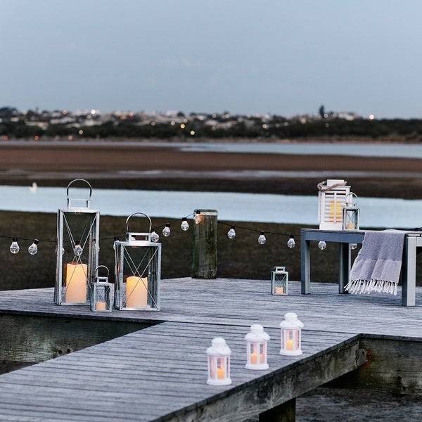 A pier on a beach with festoons and lanterns.
