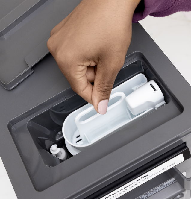 Hand retrieving a white container from a gray device.