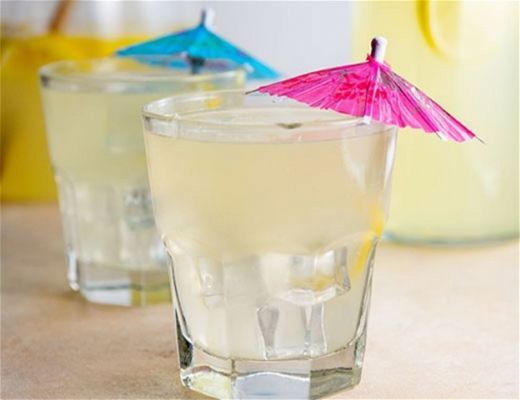Two cocktails with colorful umbrellas on a table.