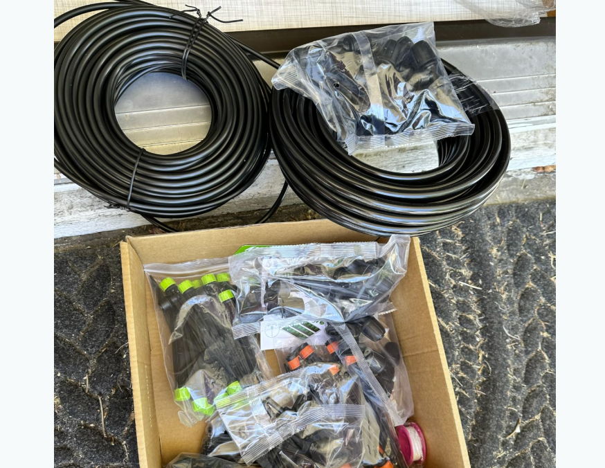 Coiled black cables and bags of assorted connectors in a cardboard box.