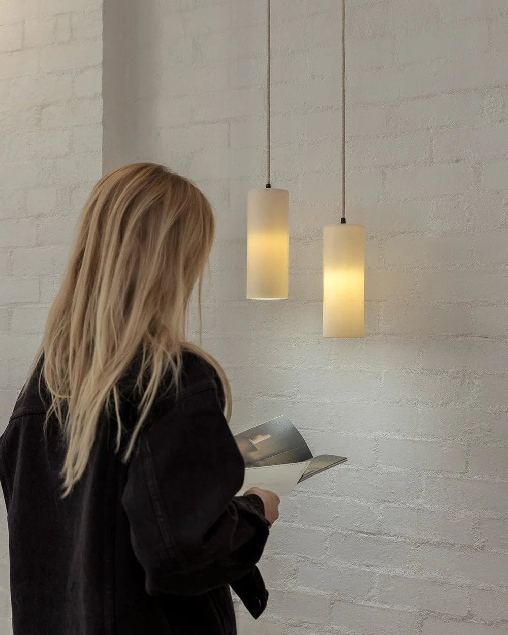 Person looking at dusked lights in a showroom with a white brick wall.
