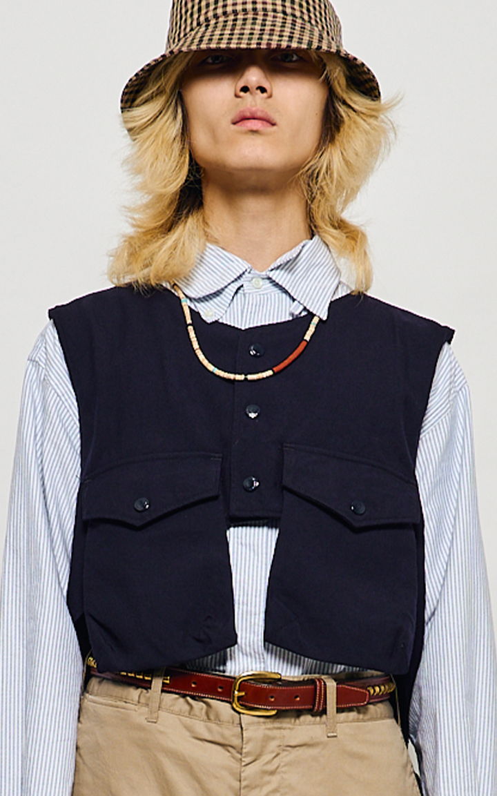 Person wearing a navy vest, striped shirt, and a patterned bucket hat.