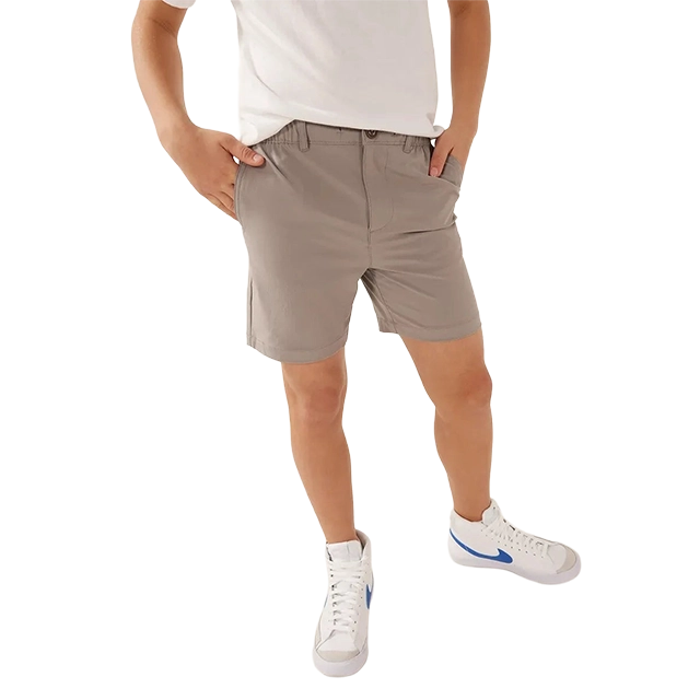 Person wearing gray shorts and white sneakers, hands in pockets.