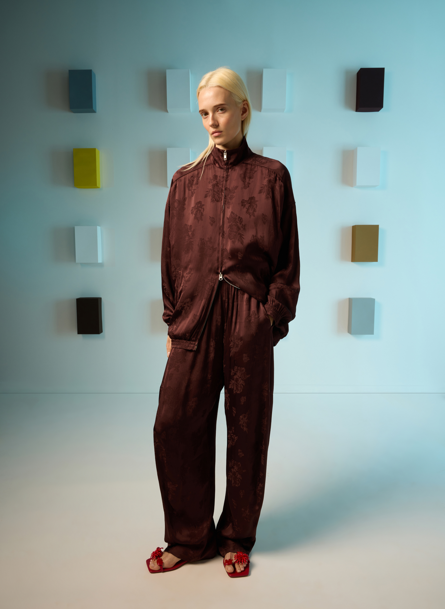Model in a stylish outfit against a colorful background.