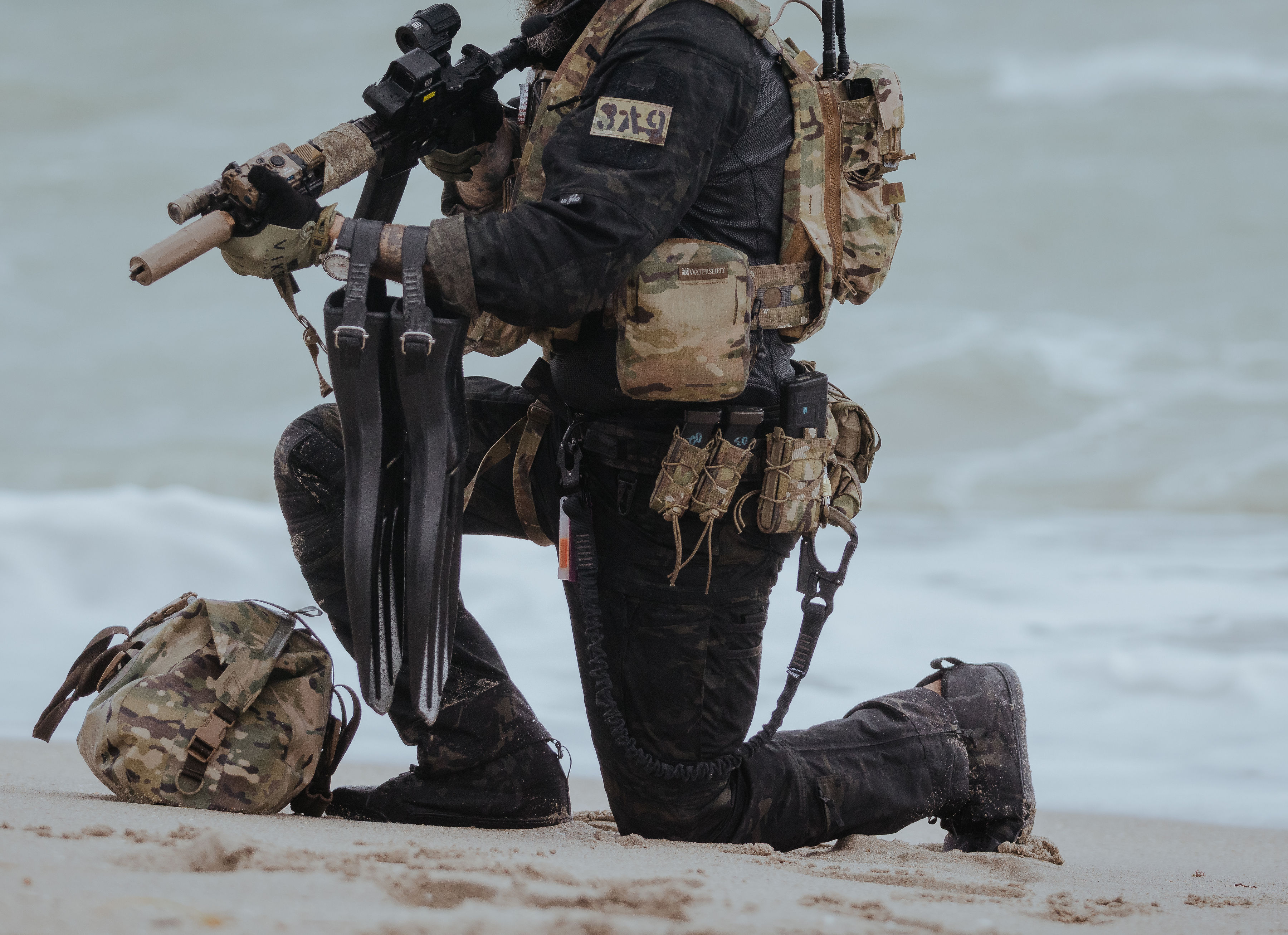 Diver kneeling on beach with waterproof gear