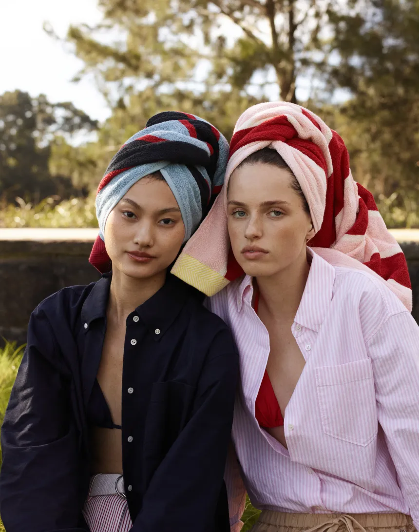 Two women with towels on their heads, posing outdoors.