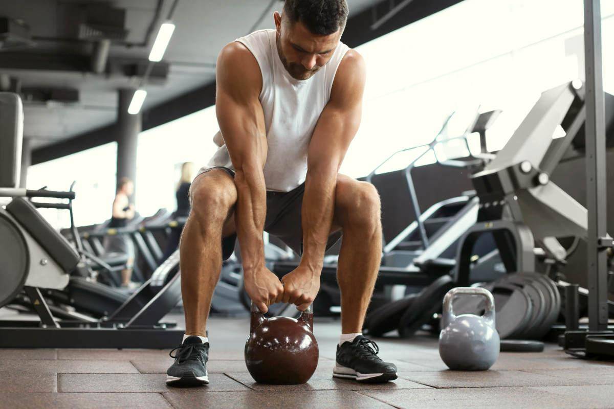 Fit and muscular man focused on lifting a dumbbell during an exercise class | Protein Powder Isolate vs. Concentrate: Which Is the Healthiest? | isolate whey