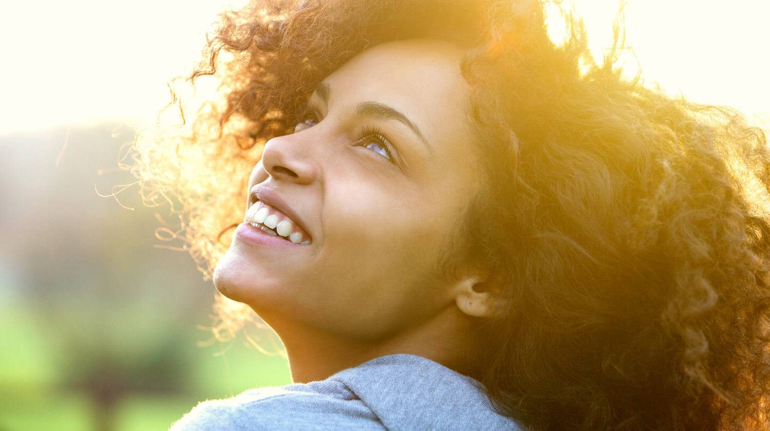 Close up portrait of a beautiful young african american woman smiling and looking up | The Power of the Mind - How Our Mindset Programs Our Cells | scarcity mindset | Featured