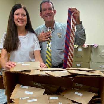 A male and female holding up neckties with packages of addressed ties