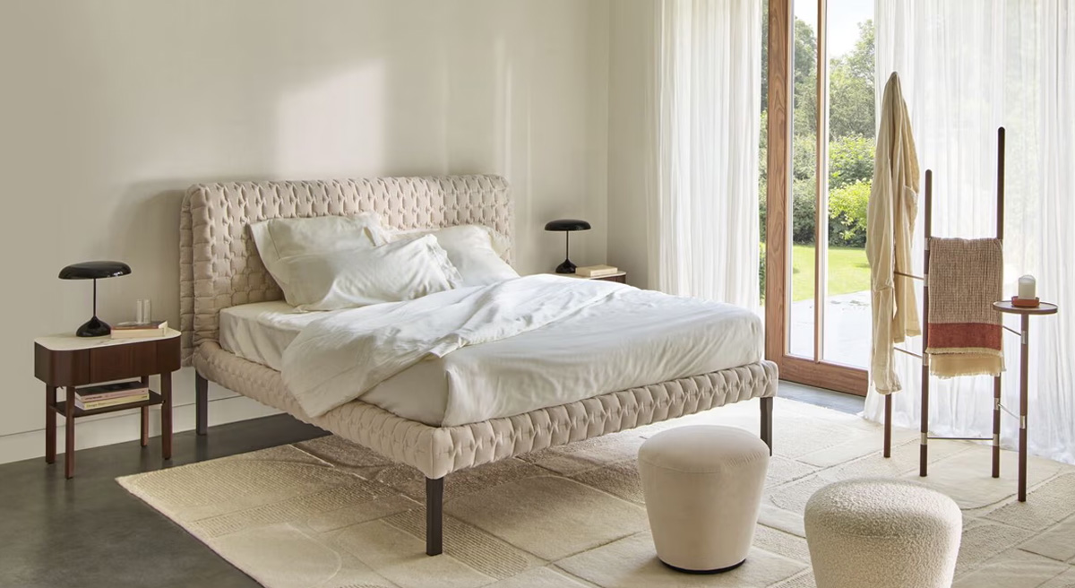 A modern Ligne Roset bedroom with a bed, side tables, and natural light.