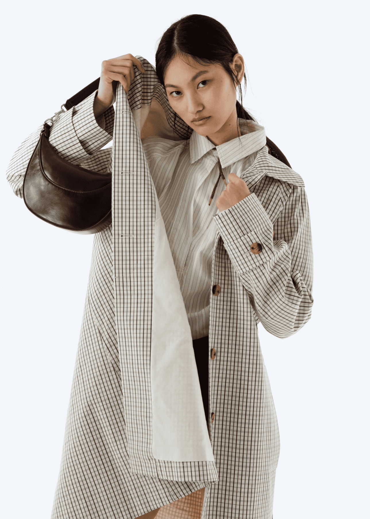 A model showcasing a stylish, checkered coat and shirt.