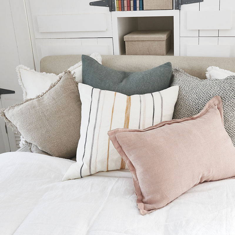 A mixture of linen cushions  on a bed