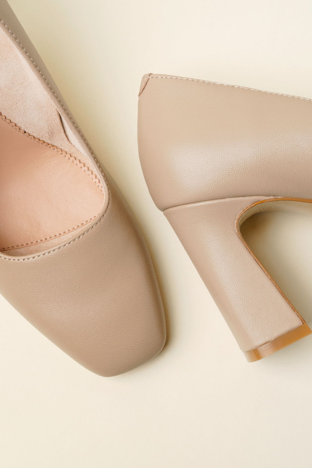 Beige high-heeled shoes on a light background.