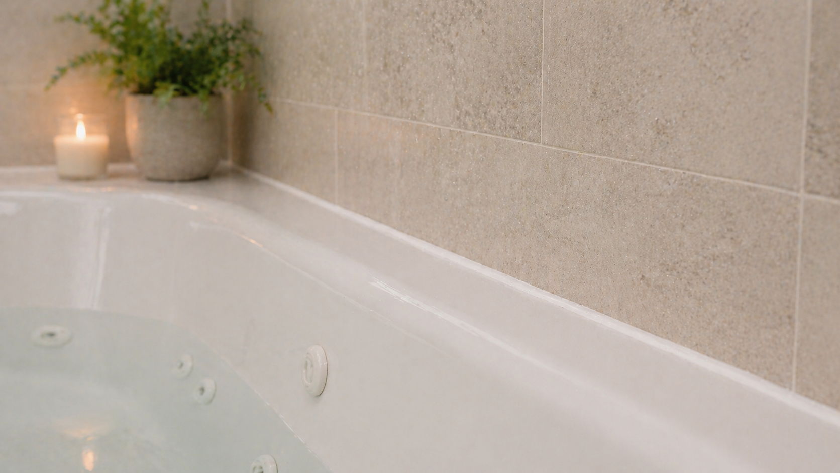 A serene bathtub with water, a candle, and a small plant.