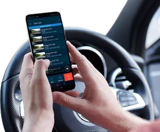 Person using a smartphone while seated in a car, with a steering wheel visible.