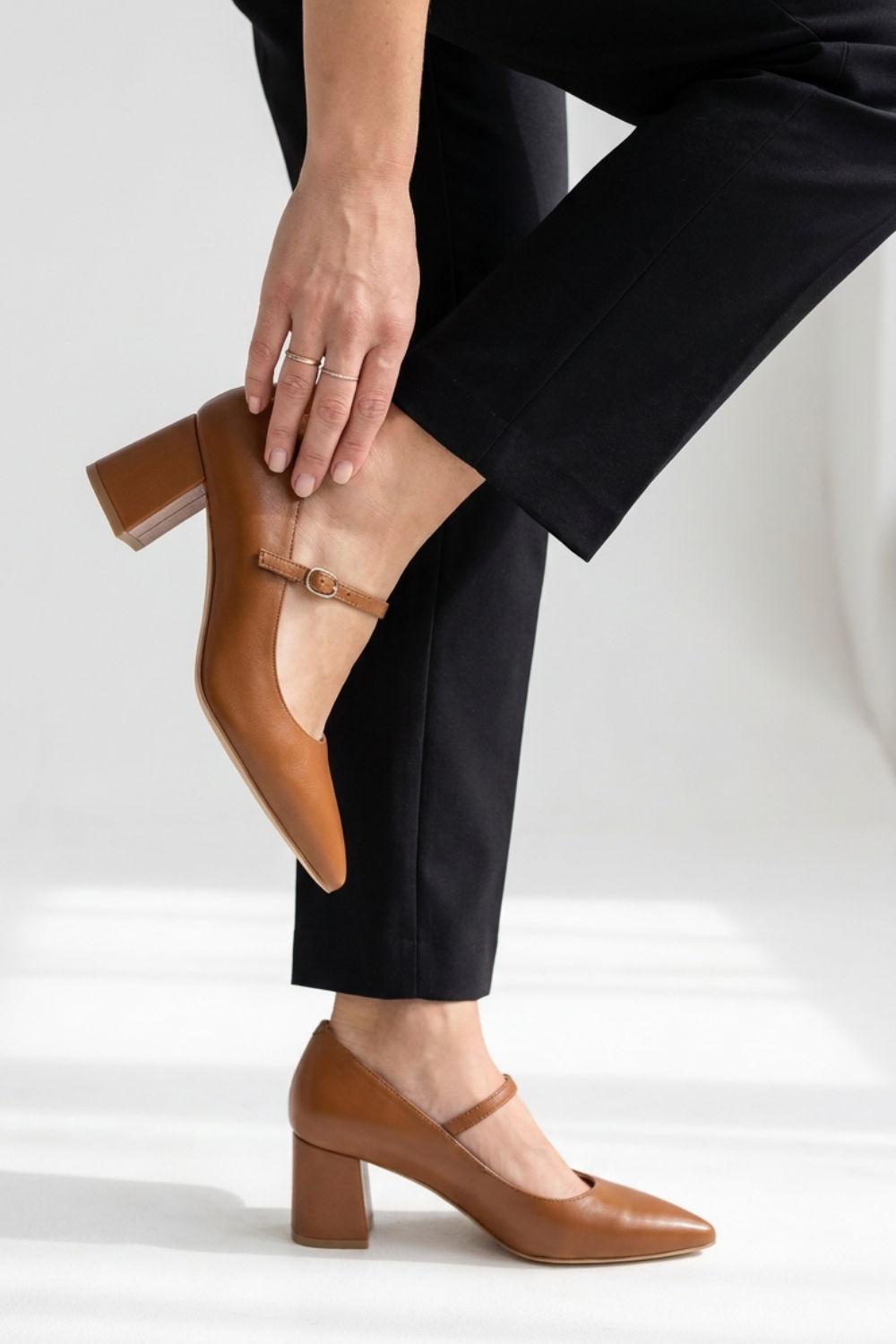 A person wearing brown heeled shoes, adjusting their footwear.