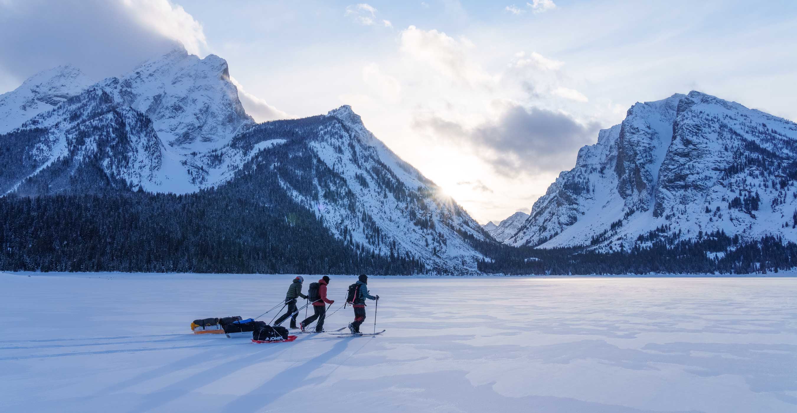 Four people splitboarding on a snowy landscape with mountains in the background.