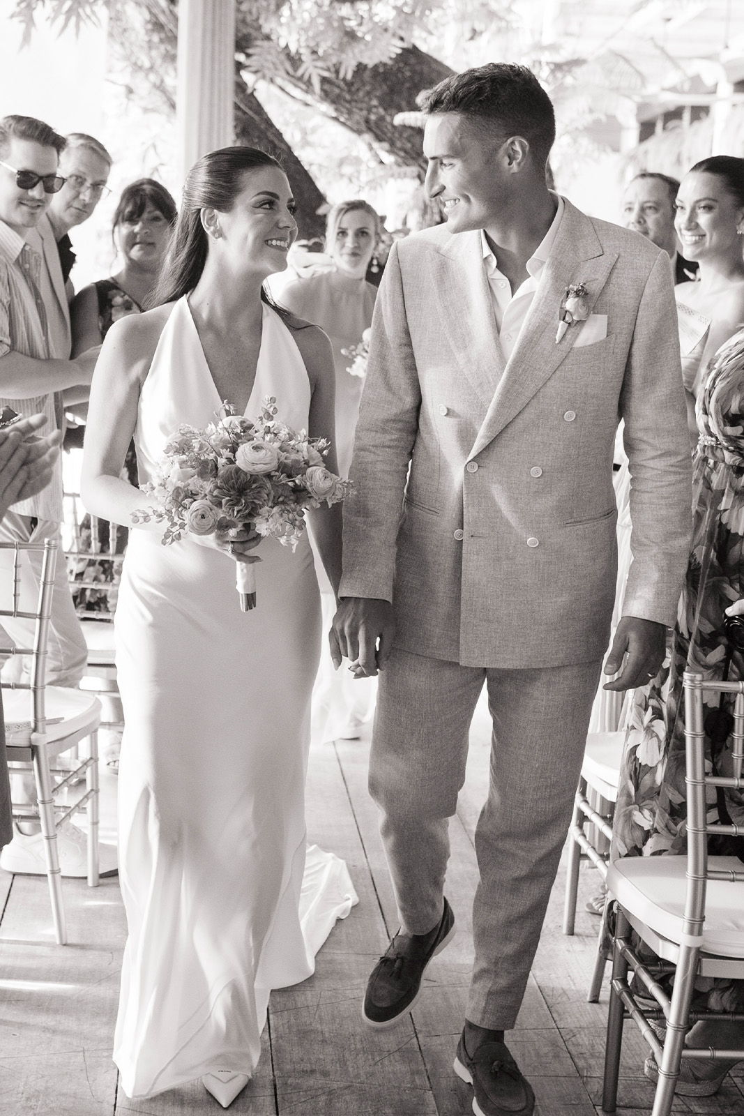 Bride and groom walking together, smiling at each other during their wedding ceremony.