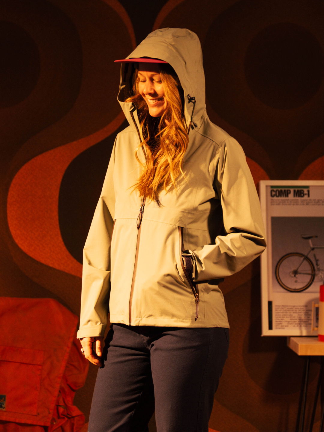 Woman wearing a light jacket with a hood, smiling on stage.