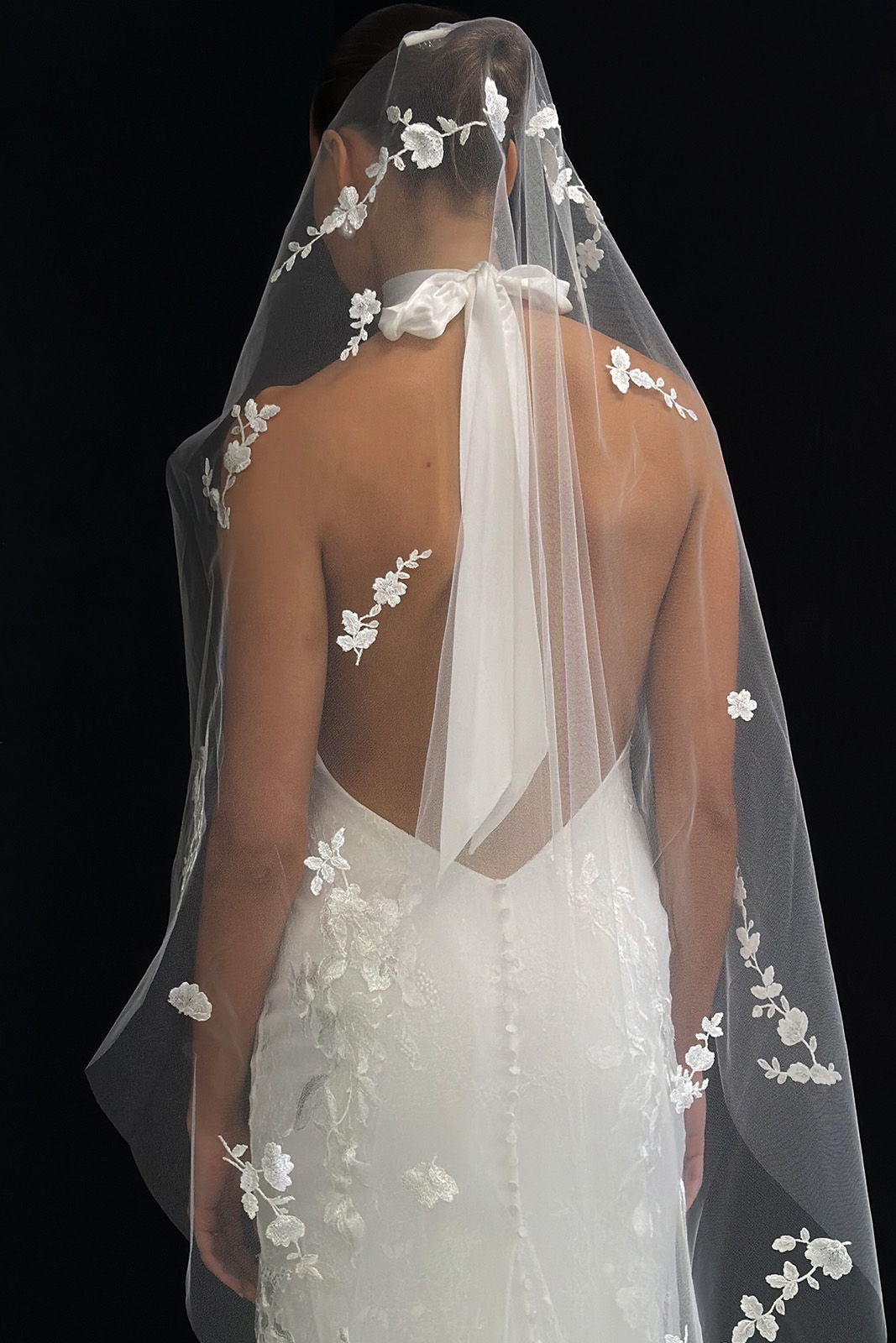 Bride in a backless wedding dress wearing a floral embellished veil.