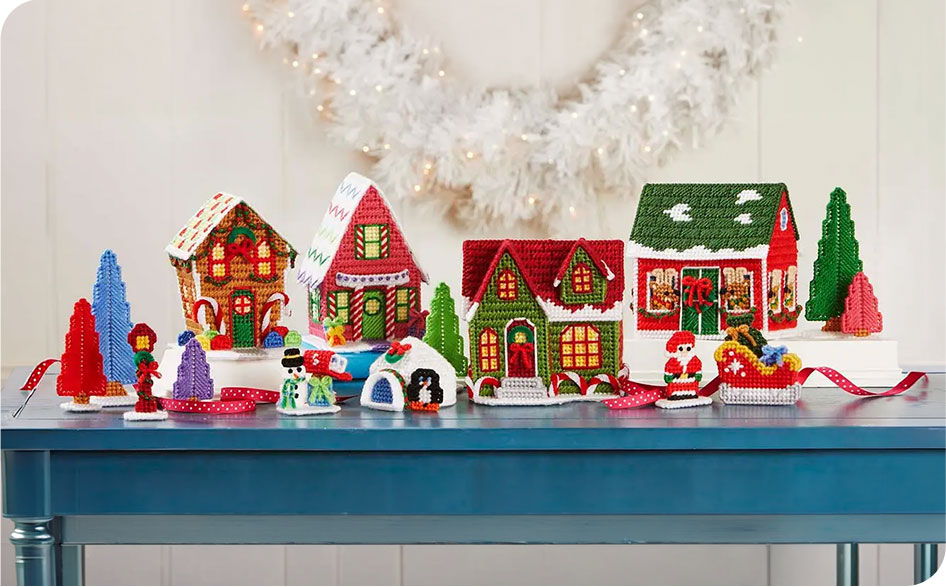 Colorful holiday village decorations on a blue table with festive trees.