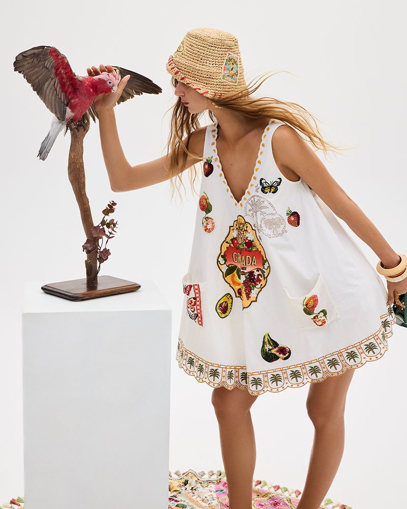 Woman in a decorated dress interacting with a bird sculpture.