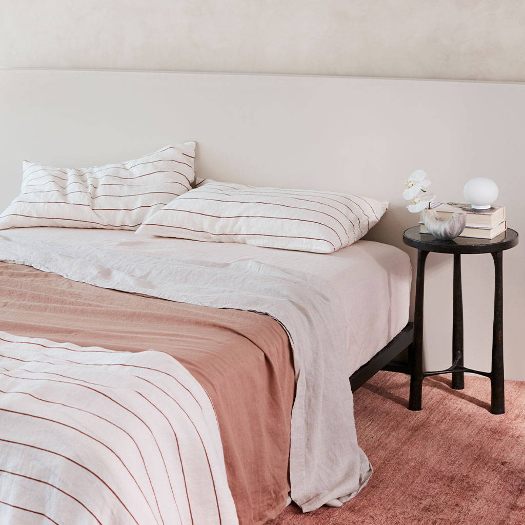 Bed styled in the Linen Fitted Sheet in White, Linen Flat Sheets in Smoke Grey, Fawn and Cedar Stripe, and Linen Pillowcases in Cedar Stripe.