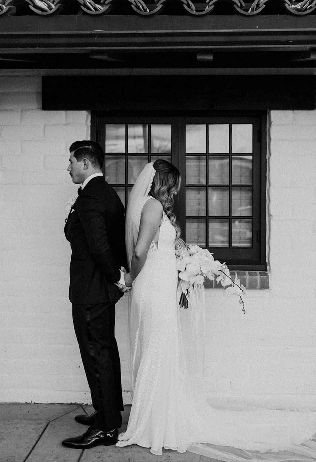 Bride and groom back to back, holding hands