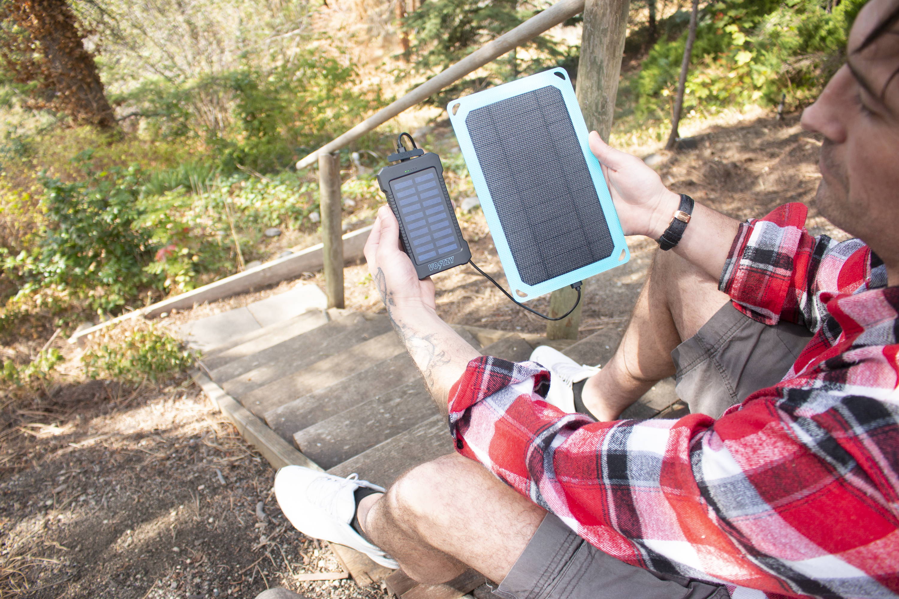 Our Brand Ambassador, Matt, holding up Voltzy Solar and Voltzy Powerbank while they charge