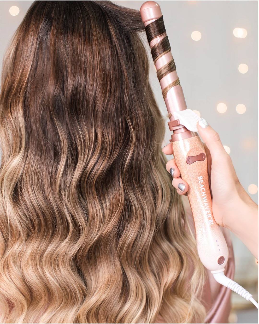 Image of pink b1 Beachwaver hair curler curlinhg a brunette with highlights hair.