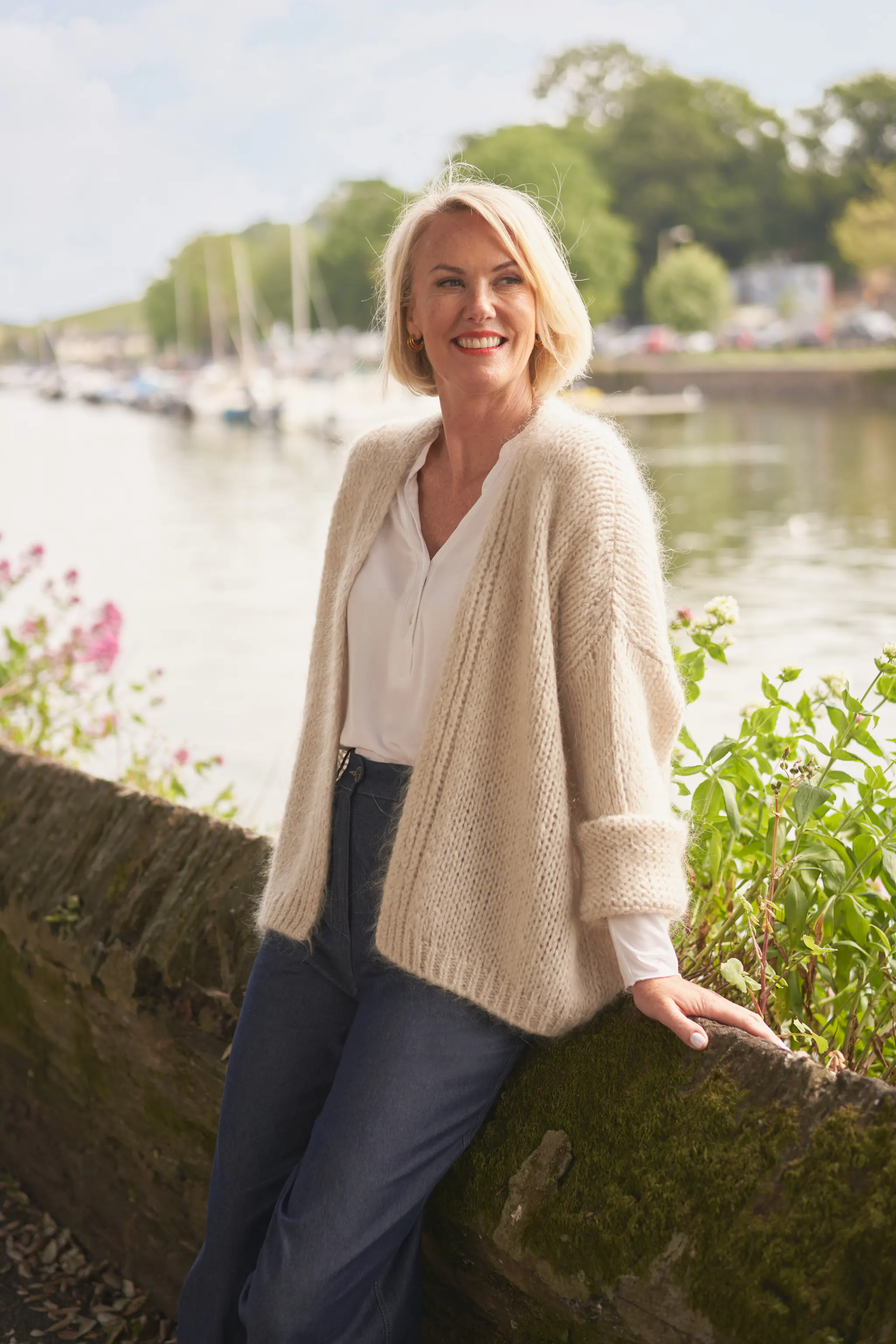 Woman wearing an oatmeal dina cardigan with blue trousers, over a white t-shirt