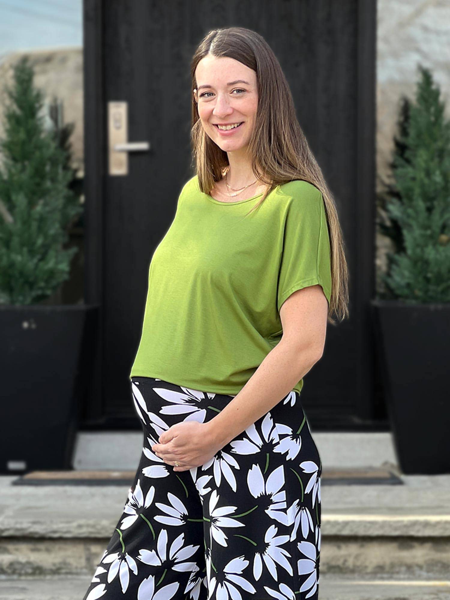 Woman wearing Miik's Adisa reversible slouchy dolman top in moss green with floral pants