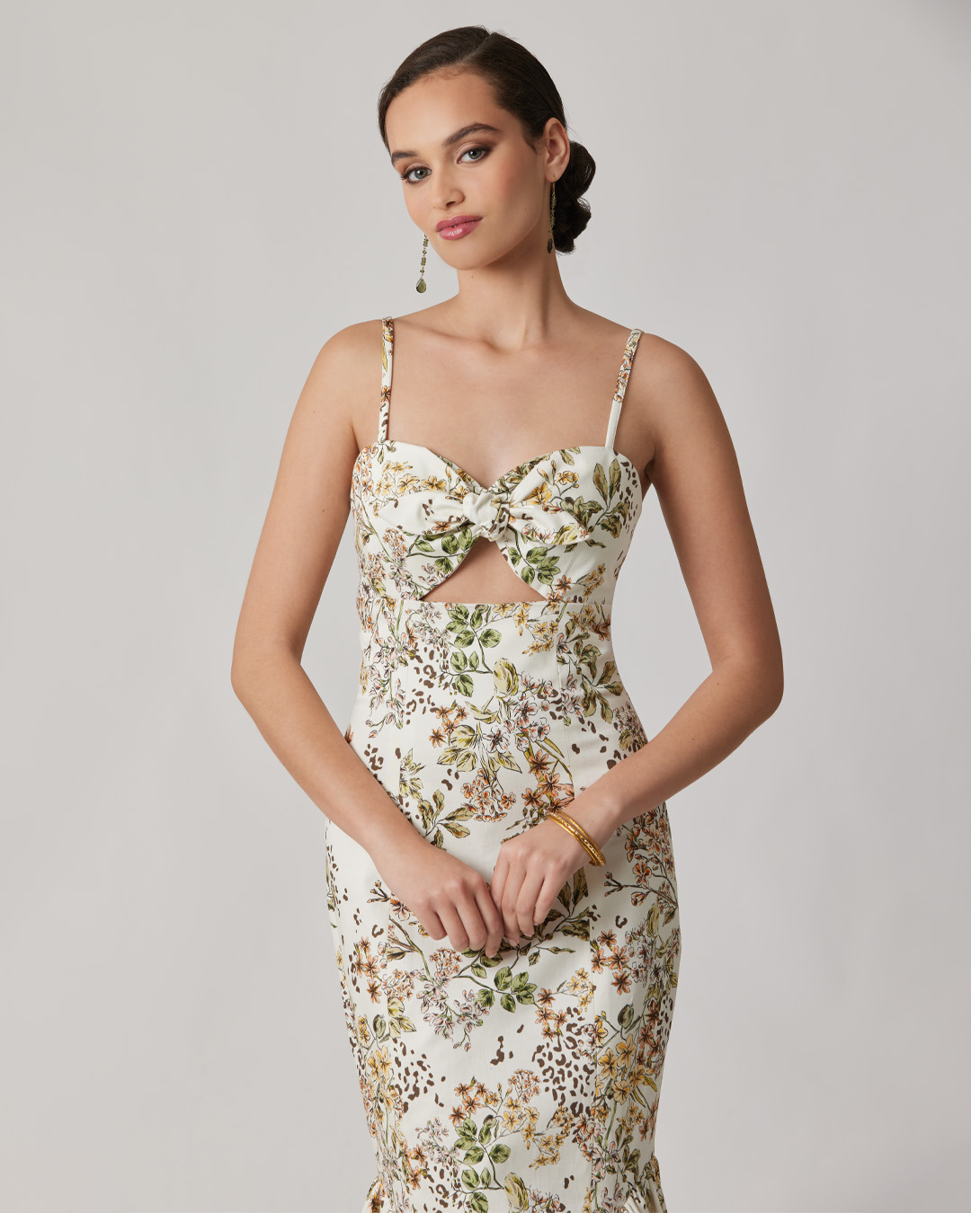 Model wearing a floral dress with cut-out design and elegant accessories.