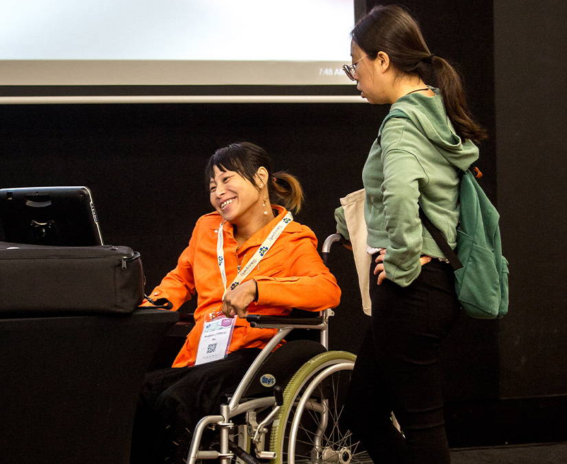 En kvinna i en rullstol som använder ett kommunikationshjälpmedel från Tobii Dynavox för att hålla en presentation