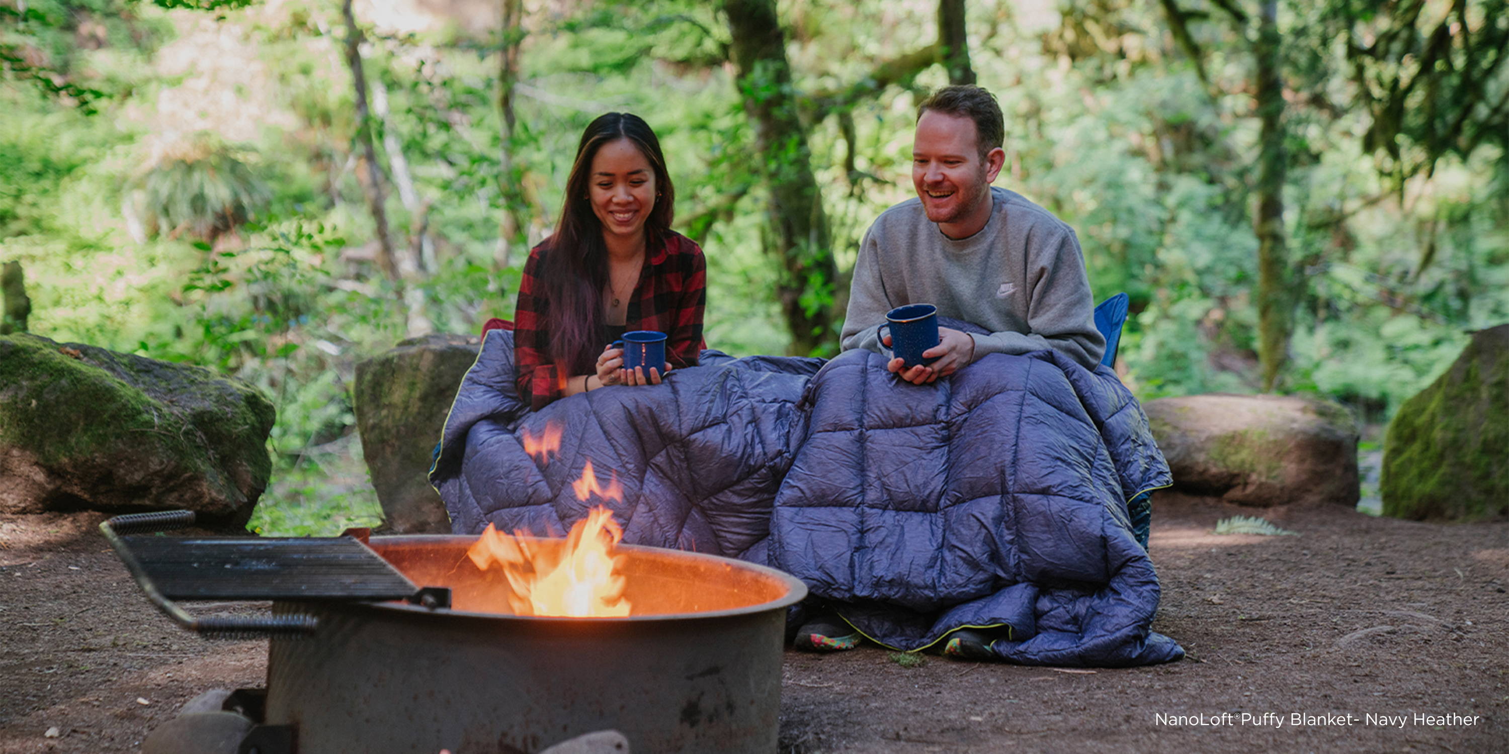 Man and woman wrapped in Rumpl Blanket in Front of Campfire