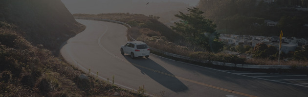 Car driving along a winding road with scenic views.