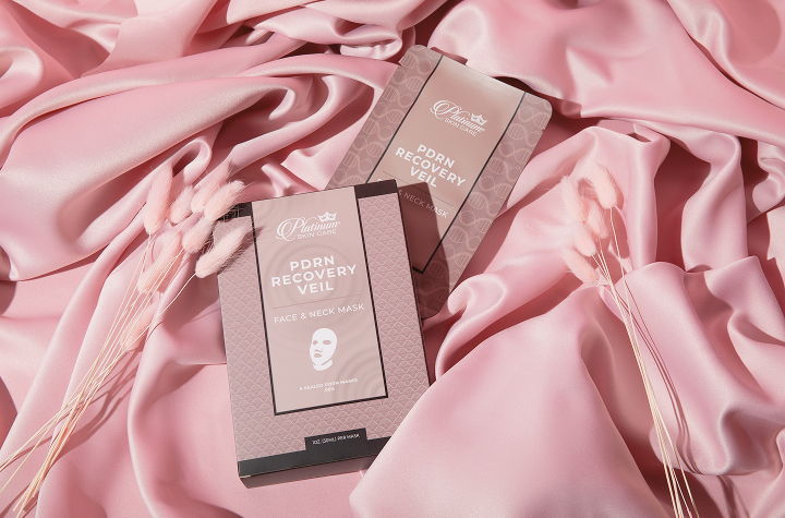 Two beauty product boxes on soft pink satin fabric.